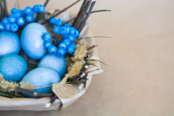 Easter holiday decorations, background. Basket with painted blue eggs, with bars, branches, flowers. Religion.