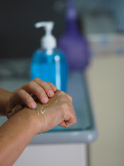 woman is standing with the finger to rub the gel alcoholic 70 percent mixture with gelatin on the...