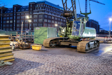 ein grüner Kran mit Kettenräder auf einer Baustelle