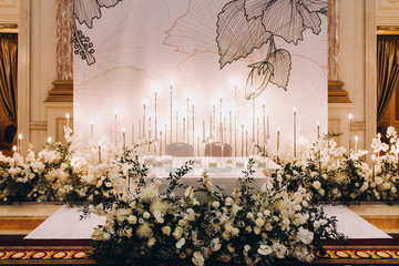 Wedding banquet. The festive table is decorated with flower arrangements and decorative lamps;...