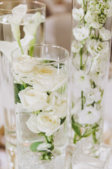 Wedding decorations. On the tables in the banquet hall are compositions of vases with water and white flowers