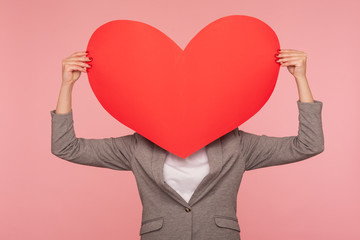 I love you! Portrait of unrecognizable woman in suit jacket hiding behind huge red heart,...