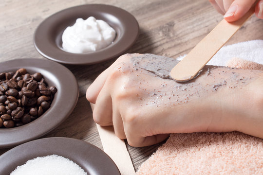 A Woman Puts A Spatula Of Coffee Homemade Scrub On Her Hand. SPA, Beauty. Ingredients For Making Scrub, Coffee Beans, Sugar, Cream. Skin Care.  Moisturizing, Exfoliating, Peeling. Home Cosmetics, Eco