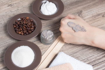 A woman applies of coffee homemade scrub on her hand. SPA, beauty. Ingredients for making a scrub, coffee beans, sugar, cream. Skin care.  Moisturizing, exfoliating, peeling. Home Cosmetics, Eco