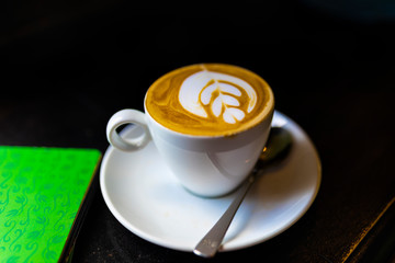 Hot art Latte Coffee in a cup on wooden table and Coffee shop blur background