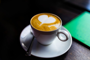 Hot art Latte Coffee in a cup on wooden table and Coffee shop blur background