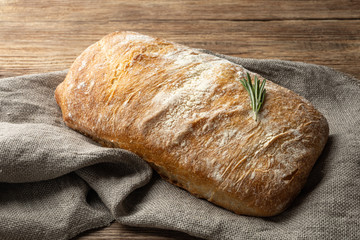 Crispy italian ciabatta bread on burlap on wooden table. - obrazy, fototapety, plakaty