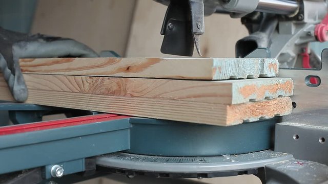 Miter saw cuts three boards. Cutting. Work with a tree. Very close plan.