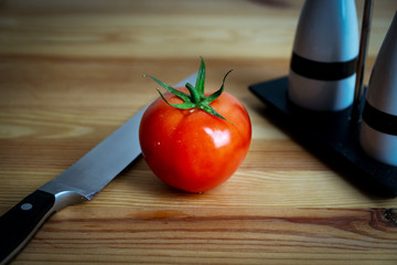 tomato lies next to a knife on the table