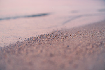 sandy beach and the edge of the water, macro shot, seashore at sunset, abstract natural background and texture retro tinted
