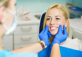 Female patient sitting in chair in dentist office for dental exam
