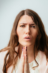 Fototapeta premium long-haired beautiful young brunette woman pleads with folded hands in front of him