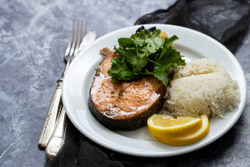 fried salmon with salad, lemon and boiled rice on white plate