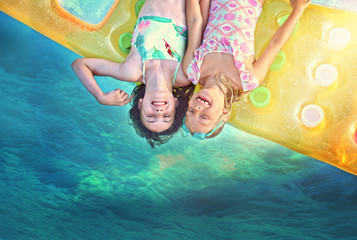 happy young kids swim on a mattress in the pool