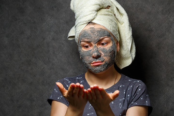 Beautiful young girl with a tonic foam mask on her face and a towel tied with hair