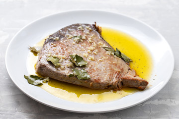 fried tuna with garlic, bay leaf and olive oil on white plate