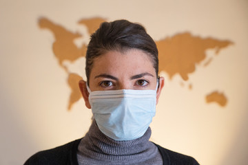 Girl with mask looking at the camera with cork world on the wall