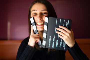 Woman smiling and picking up a movie clapboard.
