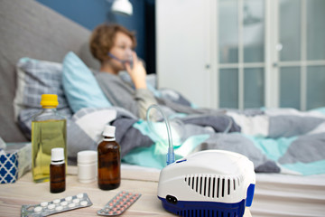 Portrait of a young woman doing inhalation at home. Use nebulizer and inhaler for the treatment....