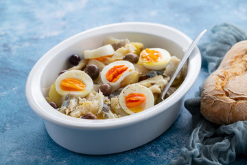 typical portuguese dish codfish with potato and egg on white dish