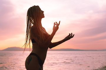 Young attractive girl with tattoo posing at sunset sea. Vacation.