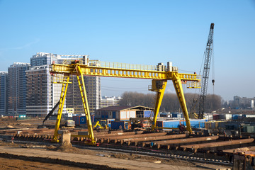 Fototapeta na wymiar Gantry crane and auto crane working at construction site. Digging a pit for the building of an underground tunnel of the metro line. Subway construction project, Minsk, Belarus, Aerodromnaya street