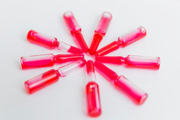 A row of ampoules with red medicine. Quarantine during the coronavirus pandemic. Vaccine against the virus. Close-up. White background.