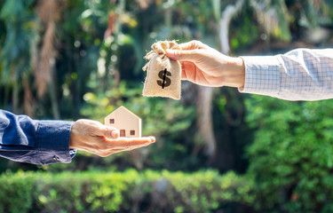 Model house and money bag in the hands of investors.Save money for buying a new home and borrowing...