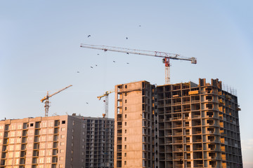 Fototapeta na wymiar Tower cranes constructing a new building at construction site.