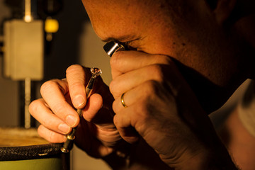 Craftsman appraising faceted gemstone.