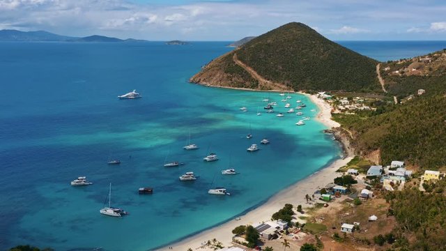 Aerial (drone) dolly shot right to left of scenic tropical island harbor with sailboats (Jost Van Dyke, British Virgin Islands)