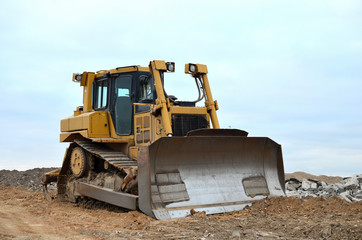 Dozer with bucket for pool excavation and utility trenching. Bulldozer during land clearing and foundation digging at construction site. Earth-moving equipment background