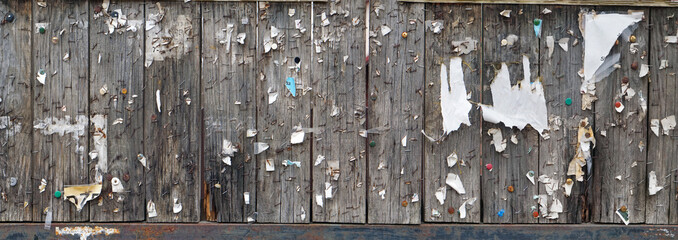 Brackets, buttons, nails and pieces of paper on a long street  wooden bulletin board panorama
