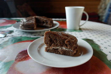 a piece of chocolate cake on a white plate. The background is blurred