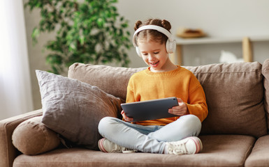 Happy girl using tablet on sofa.