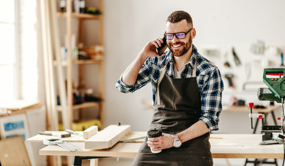 Young craftsman talking on phone in studio