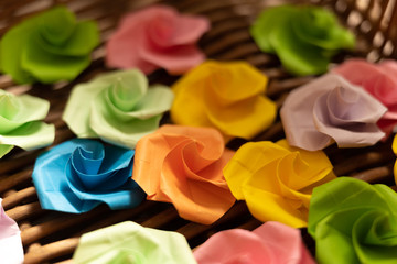 Origami paper flowers lie in a basket