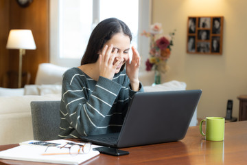 Surprised and smiling student with laptop at home