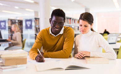 Obraz premium People reading and making notes while preparing for exam in library