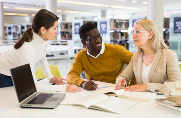 Fototapeta premium Students sitting in library, working with professor
