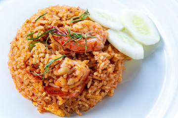 Spicy Thai food or Asia food Closeup top view Shrimp Red Curry Fried Rice seafood, Garnish with shredded kaffir lime leaves and sliced cucumber on a clean round white dish for cooking delicious meals