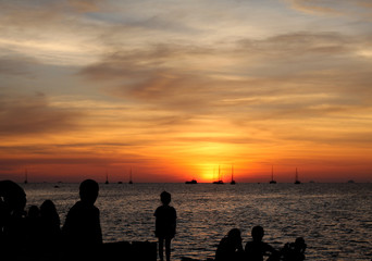 Fototapeta premium Sunset near dusk the people on the coast see many fishing boats. See in the distance