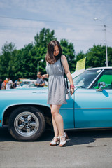 Beautiful girl on a summer sunny day near a muscle car. Blue sports car