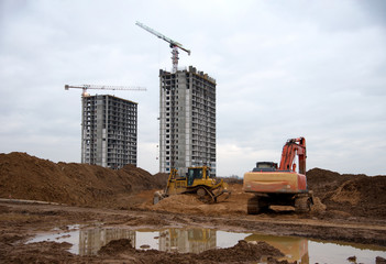 Excavtor and bulldozer digg ground at construction site for the construction of the road. Dozer during land clearing and foundation digging. Earth-moving heavy equipment