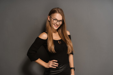 Elegant smiling woman in eyeglasses on black background