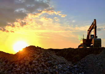 Excavator in a mining quarry at sunset. Crushing concrete  and gravel construction site or open pit