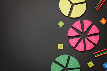 Mathematics background - fractions on black table, close up. Dividing fractions, math concept.