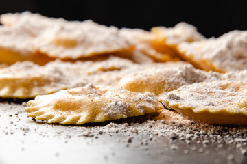 Tasty raw ravioli with flour and basil on wood table