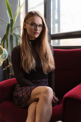 Portrait of a stunning fashionable model sitting in a red chair