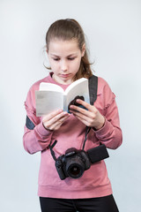Fototapeta premium Teen age girl reading service manual book for dlsr camera, beginner in learning photography, a grey background